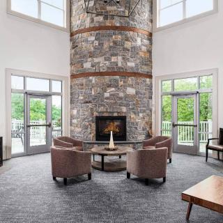 A modern living room with a tall stone fireplace and comfortable seating.