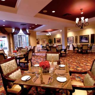 An elegant dining room with neatly arranged tables and chairs, featuring warm lighting and tasteful decor.