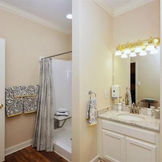 A cozy bathroom featuring a shower, sink with mirror, and neatly arranged towels.