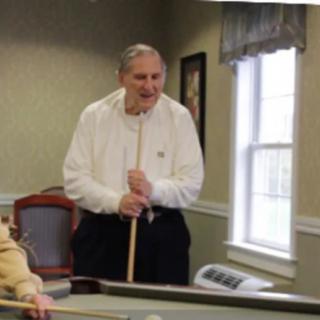 An elderly man playing a game of pool indoors.