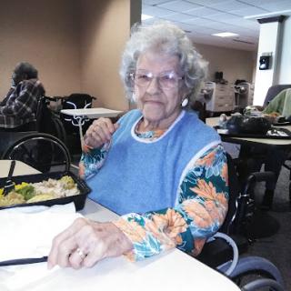 An elderly woman enjoying her meal in a cozy dining space.