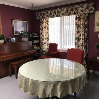 A cozy living room with a piano, round table, and floral curtains.