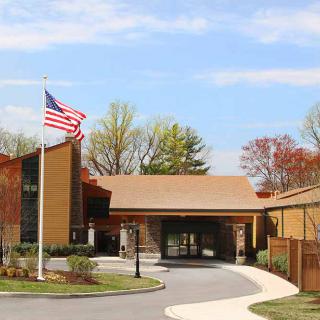 Entrance of a building with an American flag and surrounding trees.