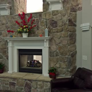 A cozy indoor setting featuring a stone fireplace with decorative flowers on the mantel and a couch nearby.
