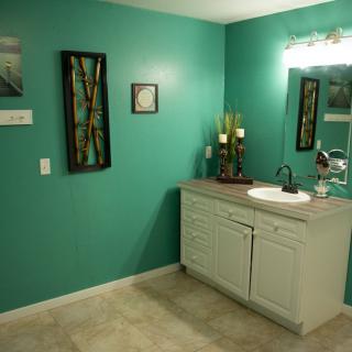 A bathroom featuring turquoise walls, a vanity with a sink, and decorative wall art.