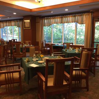An elegant dining room with neatly arranged tables and chairs, featuring large windows for natural light.
