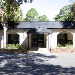 A serene view of a building entrance framed by lush greenery and shadows.