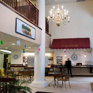 A spacious lobby with a seating area, chandelier, and a cafe counter.