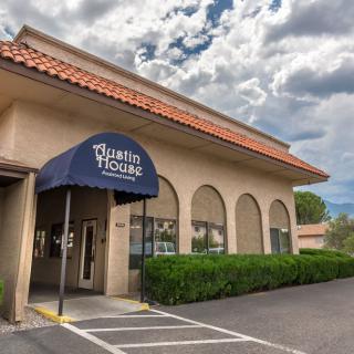 The exterior of a restaurant building with a blue awning under a cloudy sky.