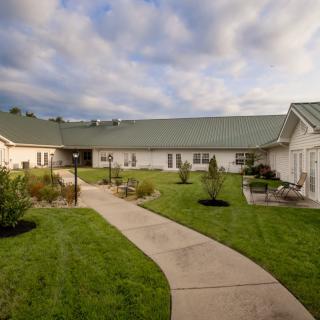 A building with a green lawn and pathway under a cloudy sky.