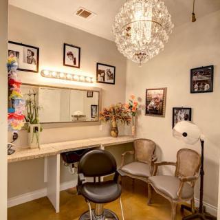 A cozy dressing room featuring a vanity with a mirror, elegant lighting, and vintage decor.