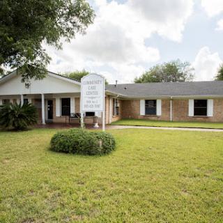 A view of a building with a well-maintained front lawn and signage under a partly cloudy sky.