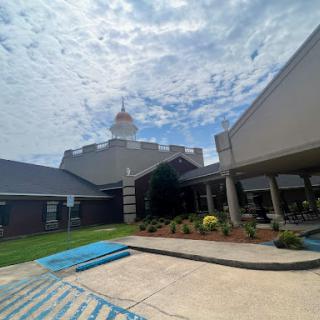A view of a modern building surrounded by greenery under a partly cloudy sky.