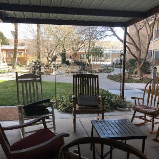 A serene outdoor patio area with rocking chairs and a view of a garden.