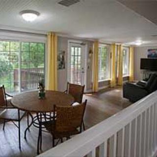 A cozy living and dining area with large windows and yellow curtains.