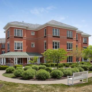A brick residential building with well-maintained hedges and a walkway.