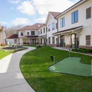 A residential building with a green courtyard, featuring a small putting green and walkways.