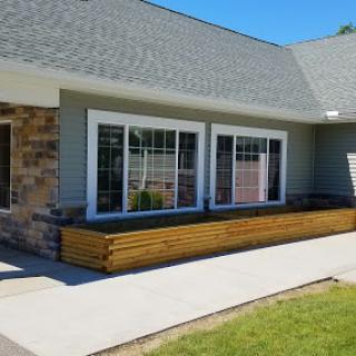 A modern building exterior featuring large windows and a wooden planter box.