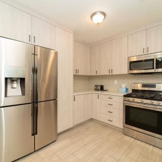 A modern kitchen with stainless steel appliances and light cabinetry.