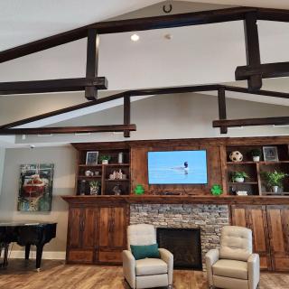 A cozy living room features wood beams, a fireplace, and built-in bookshelves.
