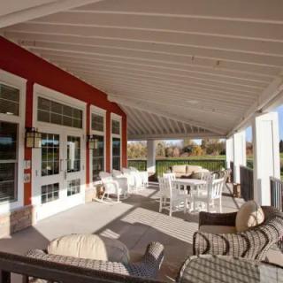 A spacious covered patio with comfortable outdoor seating and tables, perfect for enjoying a sunny day.