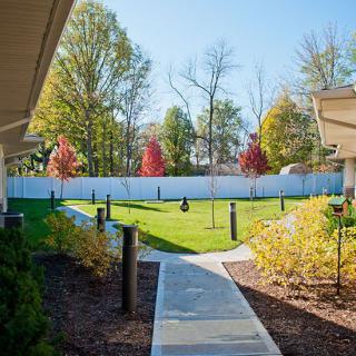 A serene garden with a pathway surrounded by trees and autumn foliage.