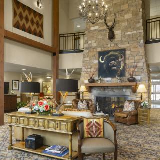 A cozy and luxurious living room with a large stone fireplace, high ceilings, and elegant decor.