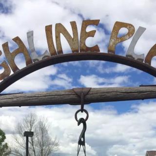 A rustic archway with the words 'HIGH LINE PLACE' against a cloudy sky.
