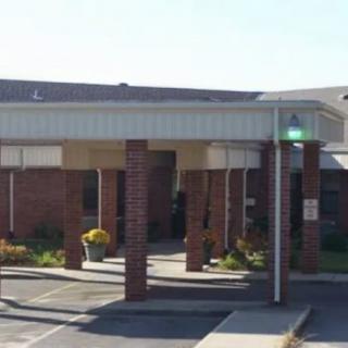 A building with a covered entrance and brick columns.