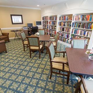 A cozy library with tables and chairs surrounded by bookshelves.