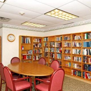 A cozy library meeting room with bookshelves, a round table, and chairs.