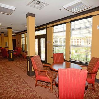A cozy dining area with several tables and chairs, featuring large windows and soft lighting.