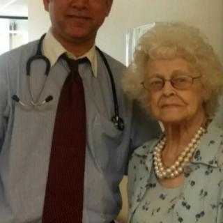 A doctor and an elderly woman standing together in a healthcare setting.