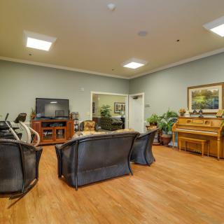 A cozy living room with a seating area, piano, exercise equipment, and a television.