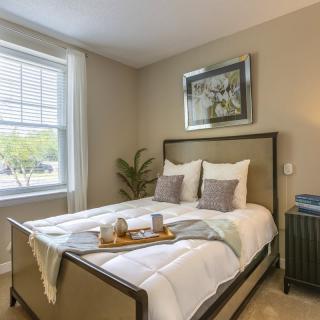 A cozy and well-decorated bedroom with a neatly made bed, soft lighting, and a tray placed on the bed for added comfort.