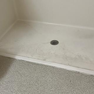 An empty shower area with a central drain in a bathroom.