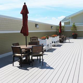 A spacious outdoor deck with seating areas and red umbrellas, perfect for relaxation on a sunny day.