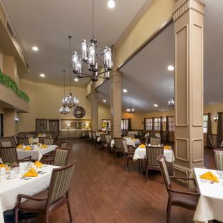 A spacious and elegantly decorated restaurant dining area with neatly arranged tables and chandeliers.