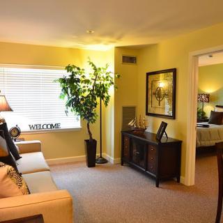 A cozy living room with warm lighting, featuring a sofa, decorative plants, and artwork on the walls.