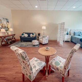 A cozy living room with a small seating area, featuring colorful patterned chairs and sofa, complemented by warm wood flooring.