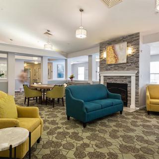 A modern living room with colorful sofas, a fireplace, and decorative artwork.