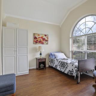 A bright bedroom with a single bed, large arched window, and minimalist decor.