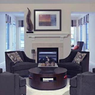 A modern living room with a central fireplace, surrounded by dark upholstered chairs and stylish decor.