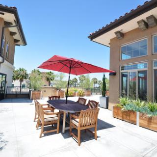 A bright and inviting outdoor dining area featuring a large red umbrella, perfect for enjoying meals in the sun.