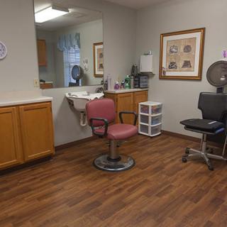A cozy hair salon with a barber chair and mirror, featuring wooden flooring.