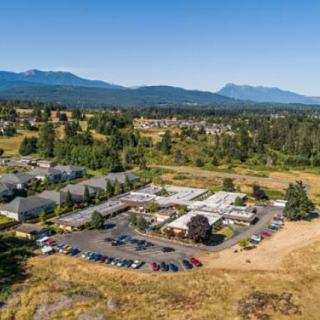 Aerial view of a rural landscape featuring buildings, a parking lot, and distant mountains.