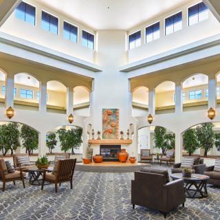 A spacious and well-lit lounge area with elegant furnishings and large windows.