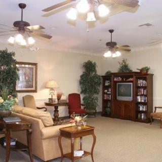 A cozy living room featuring comfortable seating, a television, bookshelves, and ceiling fans.