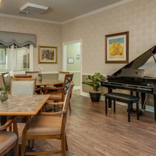 A cozy living room with a grand piano, surrounded by elegant furniture and artwork.