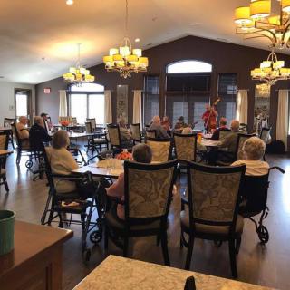 A dining area with seniors seated at tables, featuring elegant lighting and a warm atmosphere.